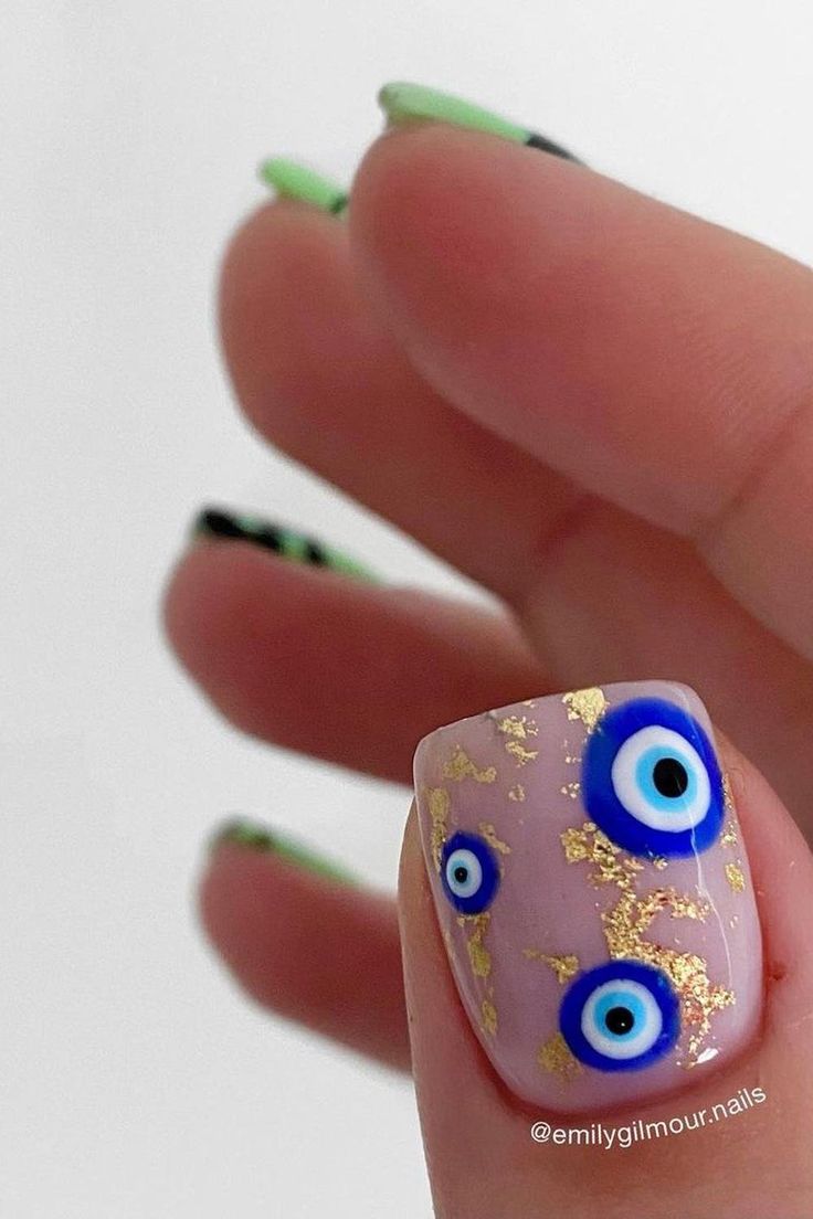 Playful Pastel Nail Design with Eye Motifs and Gold Leaf Accents.