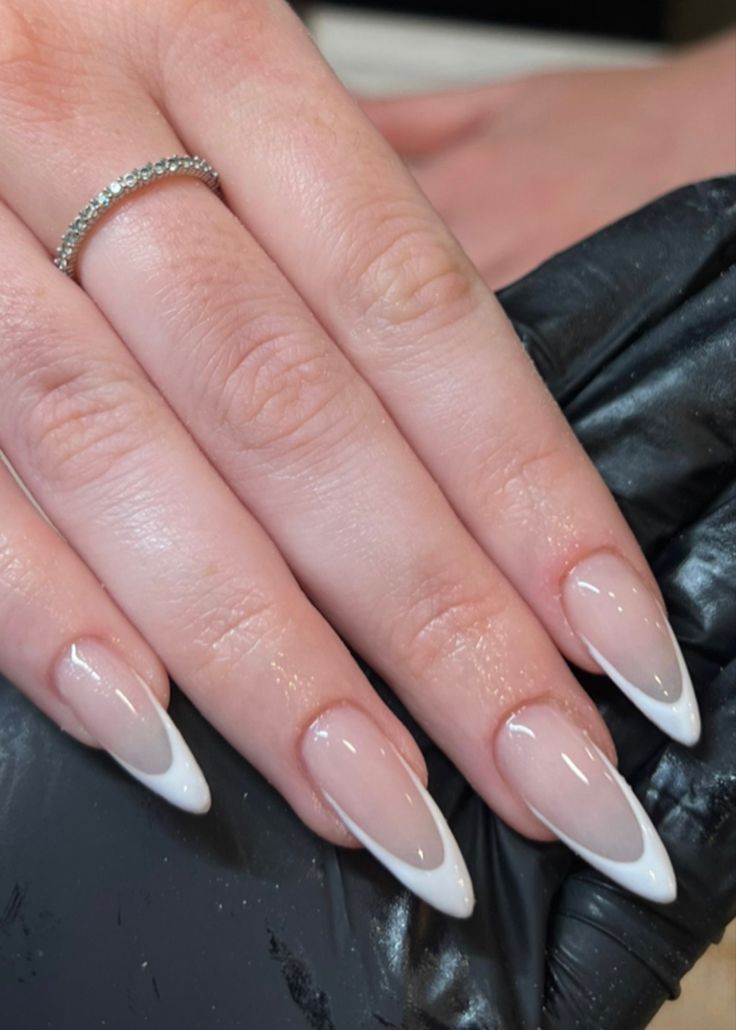 Elegant Stiletto Nails: Glossy Gradient from Soft Nude to White Tips with Minimalist Ring Accent.