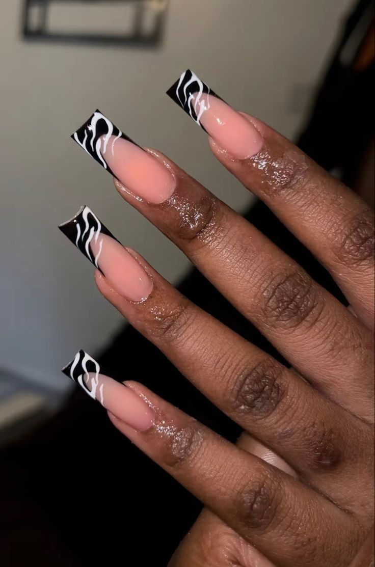 Chic Nail Design: Sophisticated Nude with Bold Black Tips and Intricate White Swirls