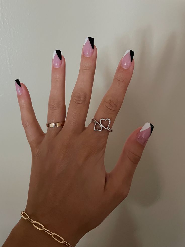 Modern Chic: Bold Black Tips Enhance Classic French Manicure with Soft Pink and Delicate Rings.