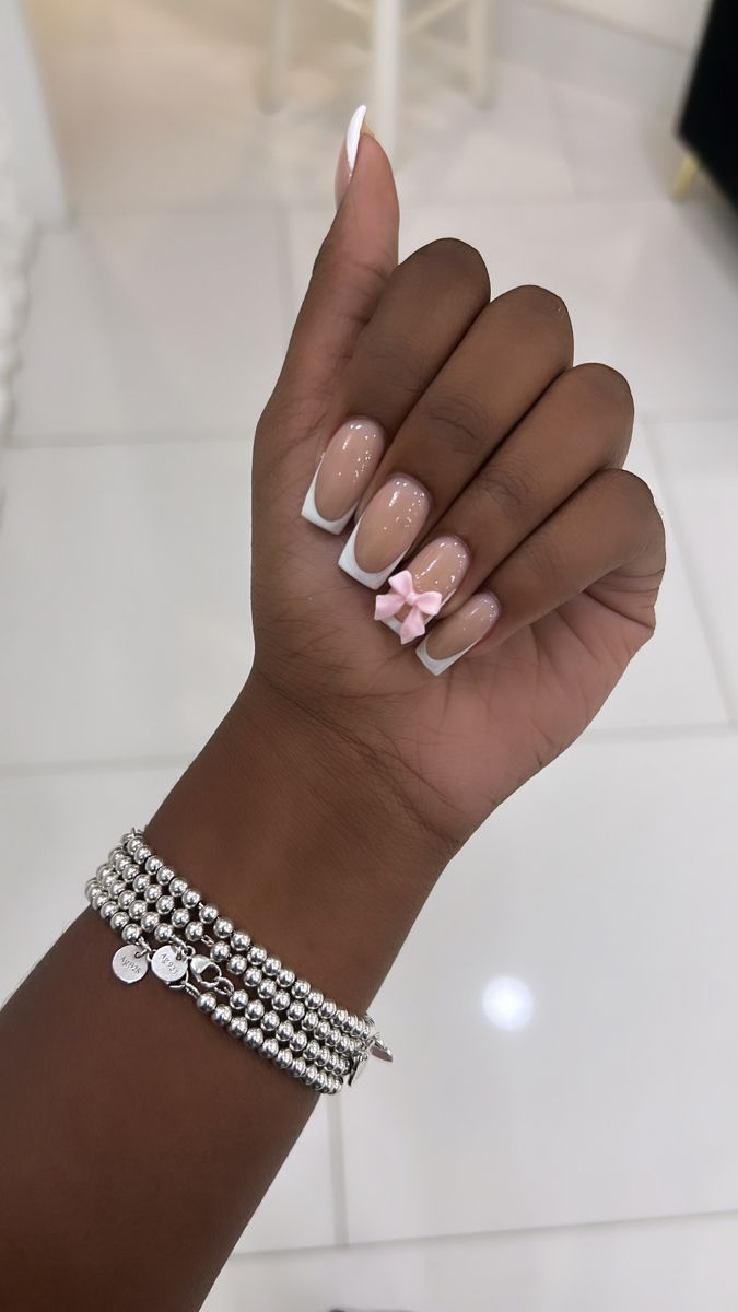 Timeless French Manicure with Playful Pink Bow and Elegant Silver Bracelet.