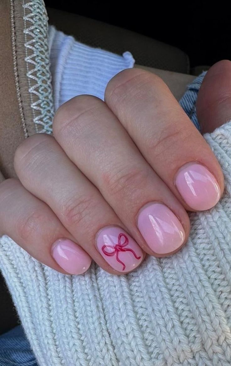 Whimsical Pink Manicure with Glossy Finish and Playful Red Bow Design.