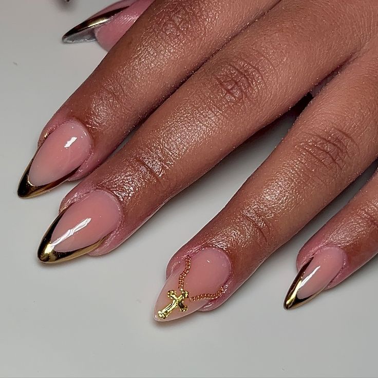 Chic Nude and Gold Nail Design with Glamorous Accent Cross Charm.