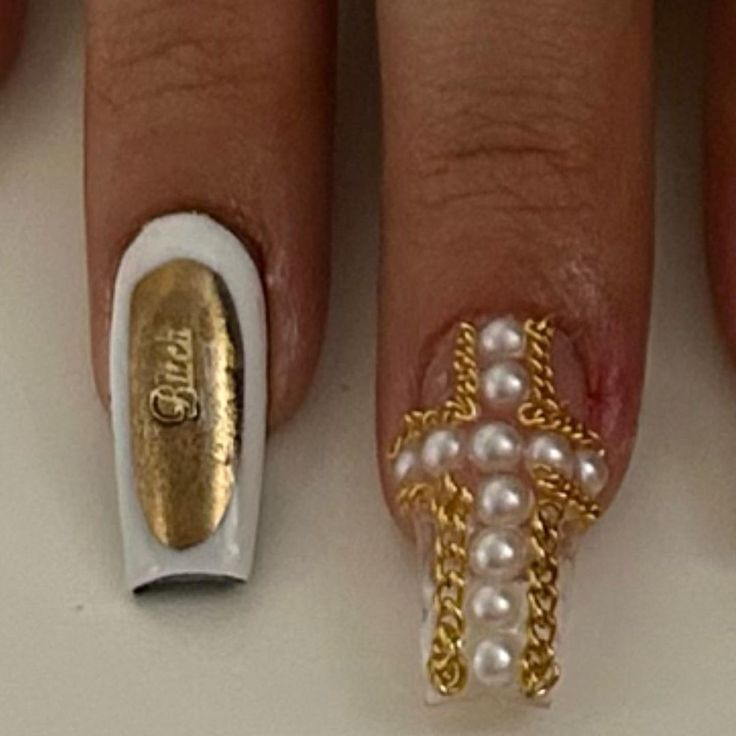 Elegant Nail Design: Stylish White Base with Gold Accents and Pearl-Embellished Chain Cross.