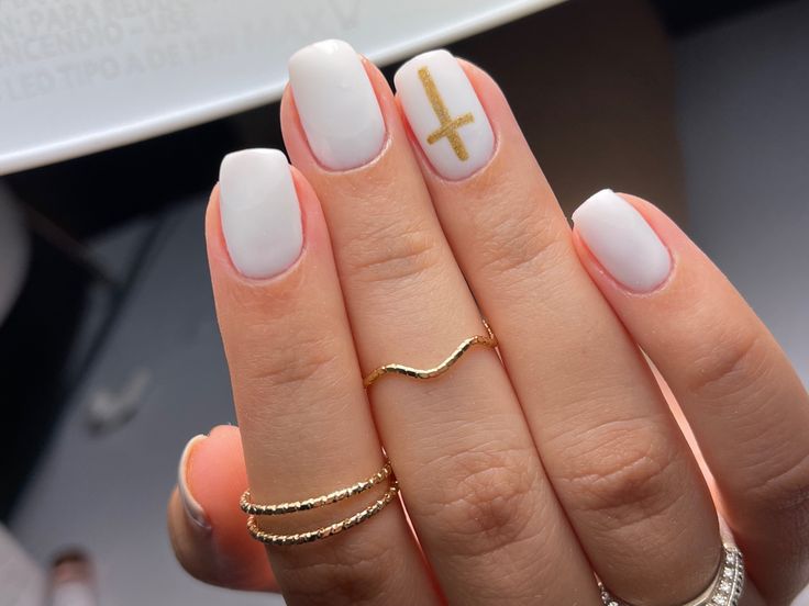 Chic Minimalist White Nails with Gold Cross Accent and Delicate Rings.