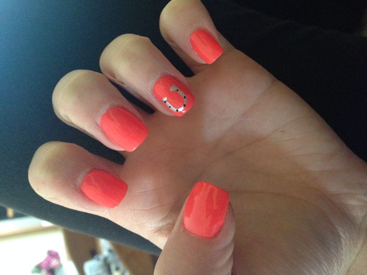 Cheerful Glossy Coral Nail Design with Playful Horseshoe Accent.