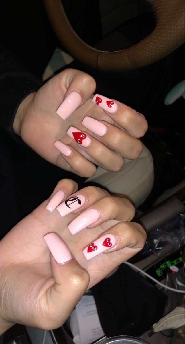 Chic Pink Nail Design with Playful Red Heart Accents and Unique Details.