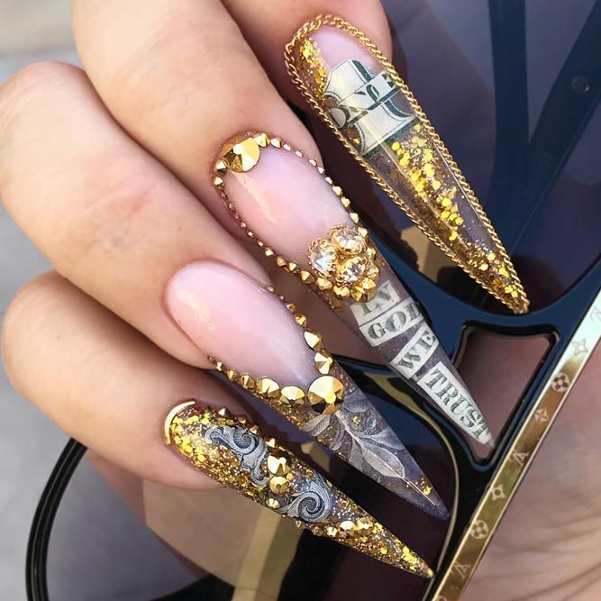 Glamorous Elongated Stiletto Nail Design with Gold Embellishments and Sparkling Rhinestones.