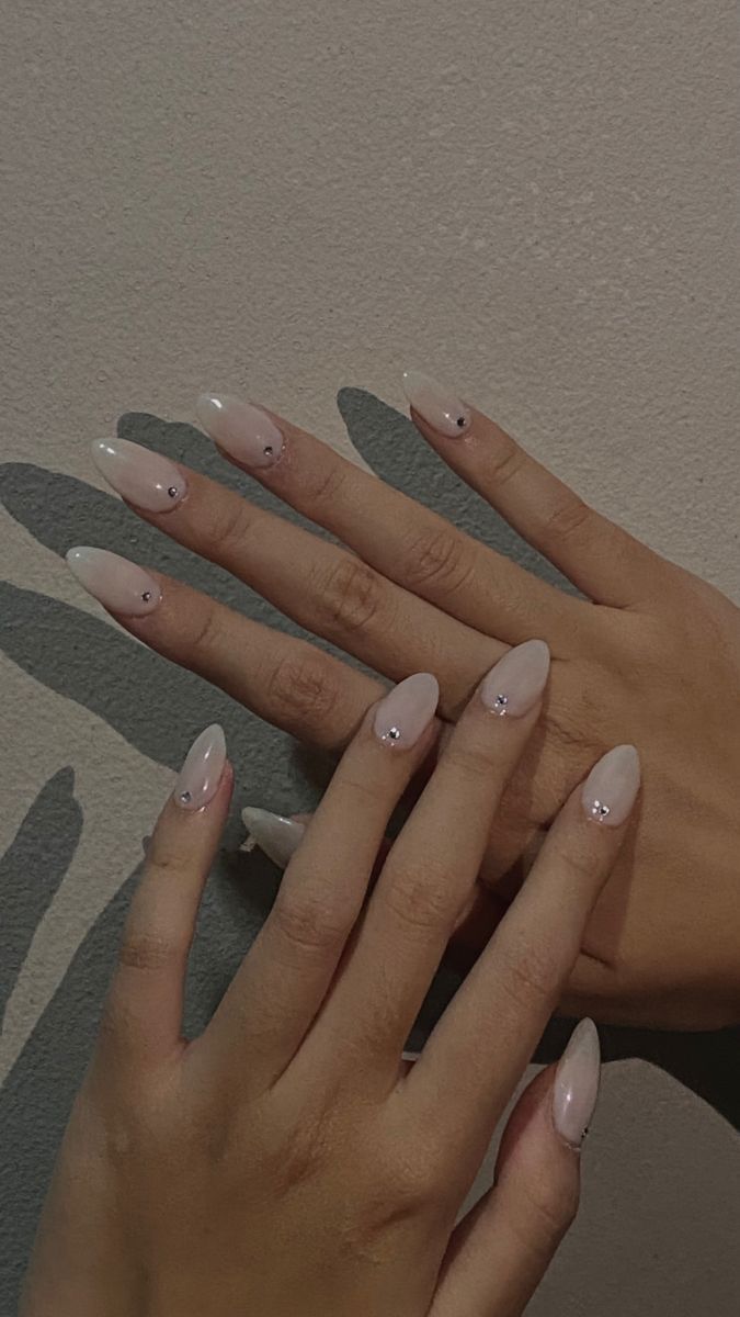 Sophisticated Almond-Shaped Nails with Nude Polish and Delicate Stone Embellishments.