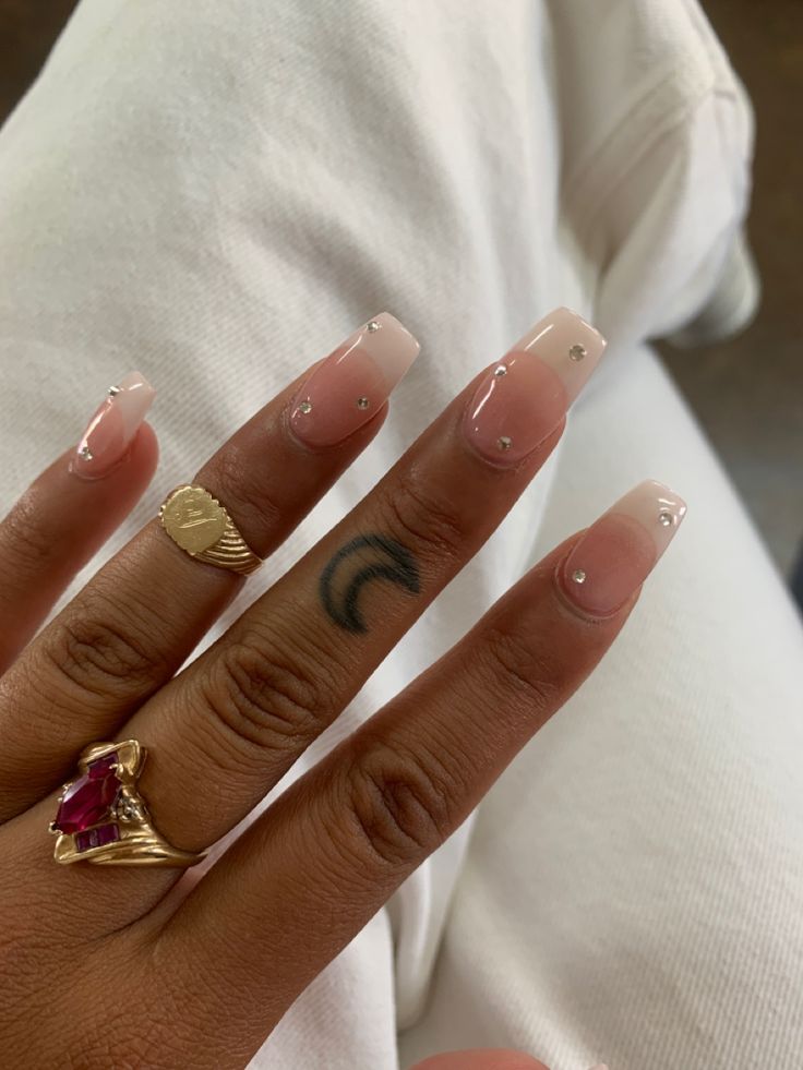 Sophisticated Nude Gradient Nail Design with Diamond Accents and Personal Tattoo Flair.