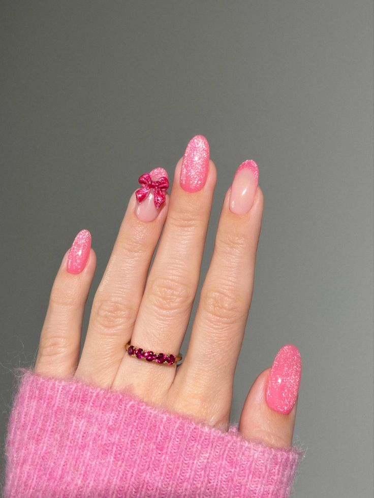 Charming Vibrant Pink Nail Design with Sparkly Accents and Playful Bow Touch.