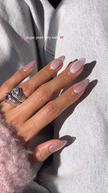 Whimsical Almond-Shaped Nails with Sparkling Pastel Pink Polish and Chic Ring Accents.