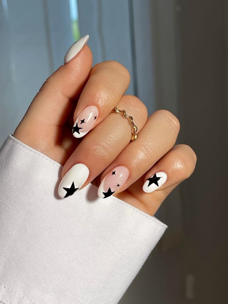 Chic Nail Design: Soft Pink and White with Bold Black Star Accents.