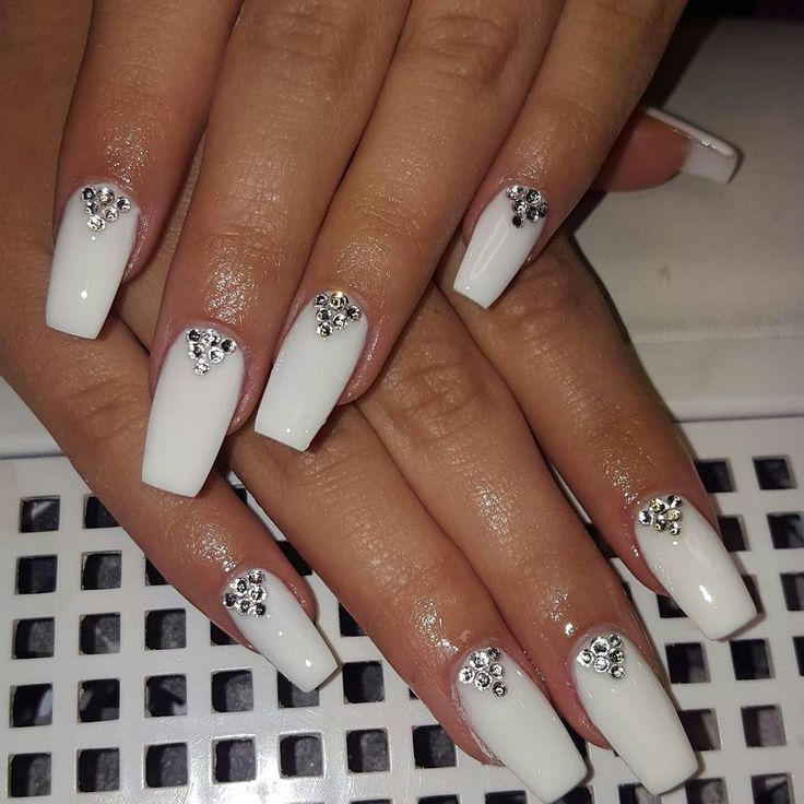 Chic White Acrylic Nails Enhanced with Sparkling Gemstone Embellishments.