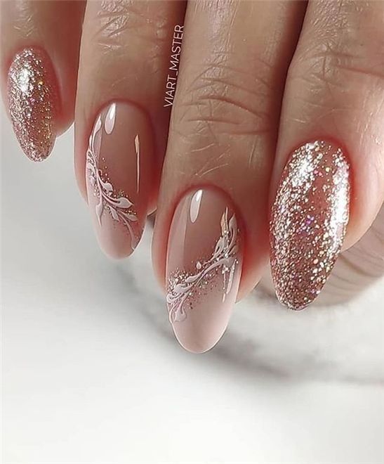 Chic Glossy Nude and Sparkling Gold Nail Design with Delicate Floral Accents for Glamorous Occasions.