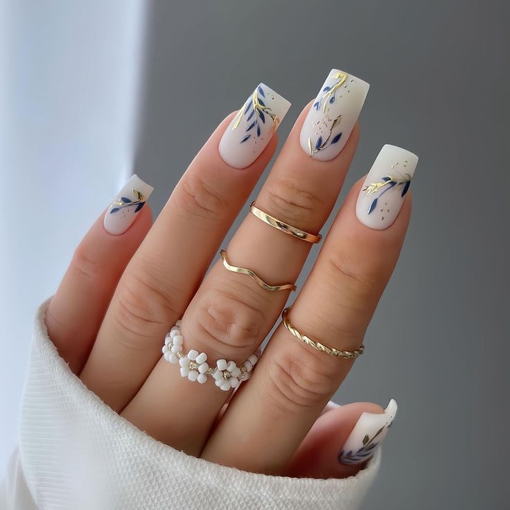 Elegant Floral Nail Design: Soft White Base with Blue and Gold Accents