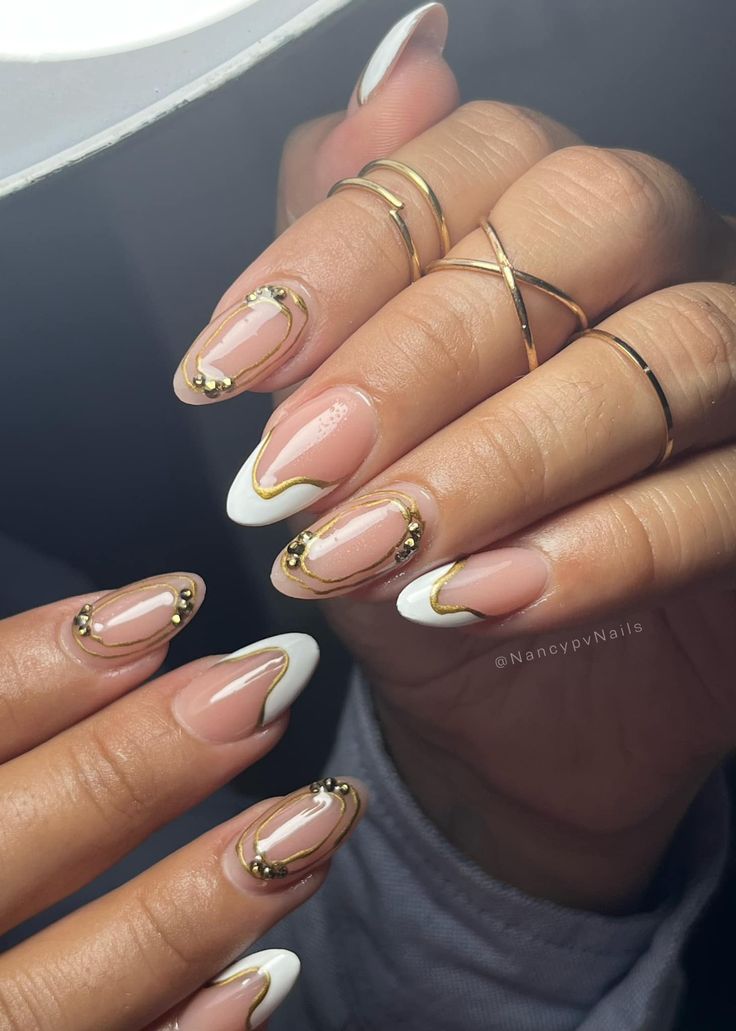 Chic Nude and White Nail Design with Intricate Gold Accents for a Glamorous Look.