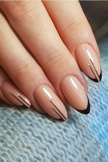 Chic Minimalist Nude Nail Design with Sharp Black Tips and Sophisticated Gold Accents.