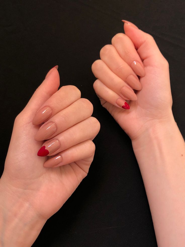 Sophisticated Nude Nail Design with Playful Red Accents and Charming Heart Details.