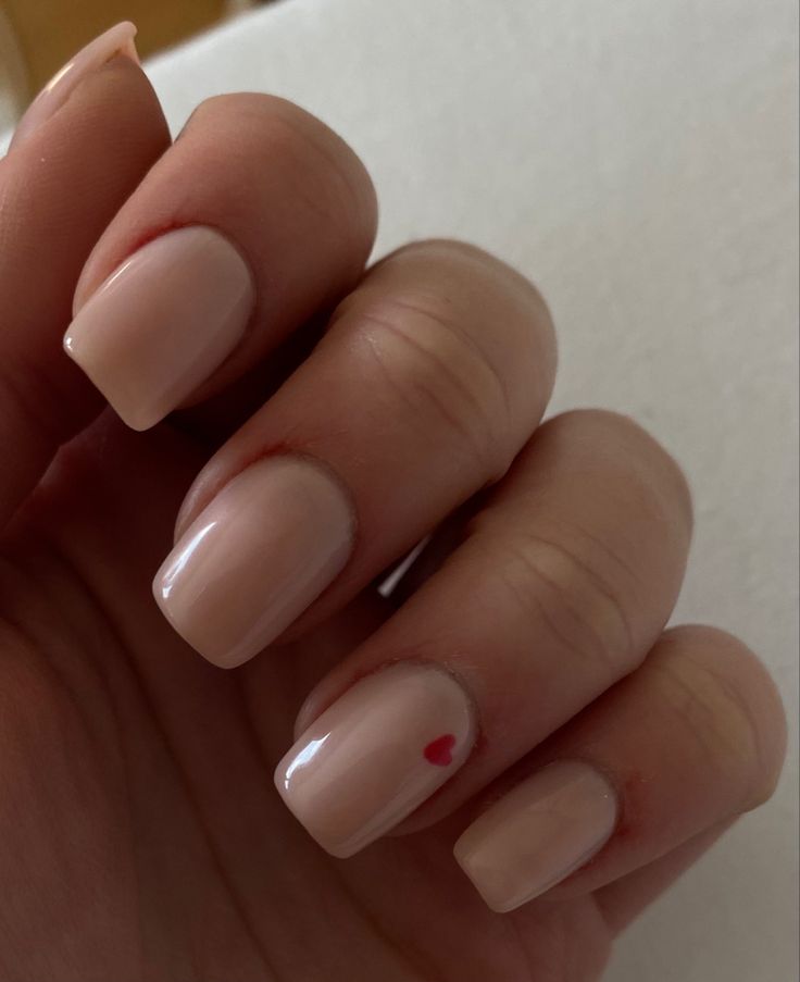 Chic Nude Nail Design with Playful Red Heart Accent