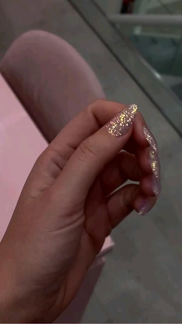 Glamorous Glittery Nail Design with Shimmering Gold and Translucent Finishes for Elegant Occasions.