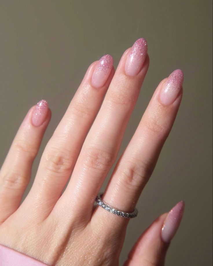 Elegant Ombre Almond-Shaped Nails with Sparkling Pink Tips and Glamorous Statement Ring.