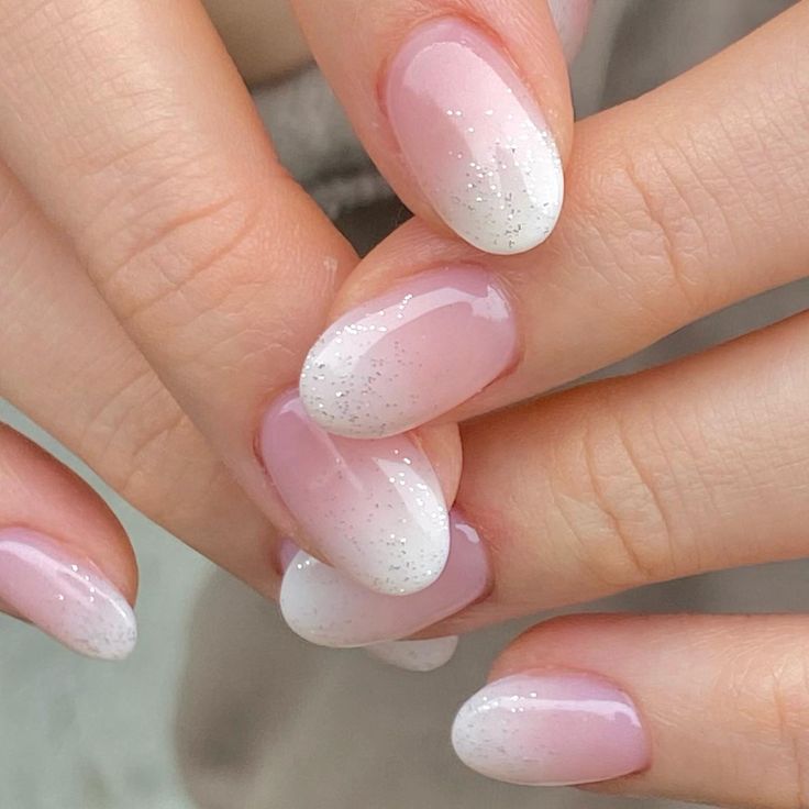 Sophisticated Ombre Nail Design: Pale Pink and White Tips with Subtle Glitter Accents.