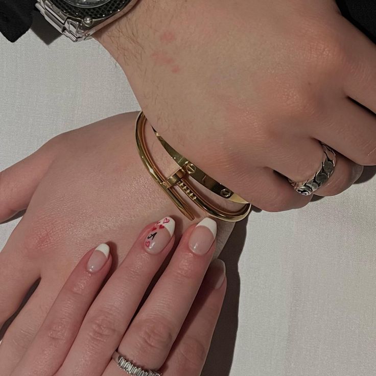 Sophisticated Floral French Tip Nail Design with Subtle Pink Base and Elegant Bracelet Styling.