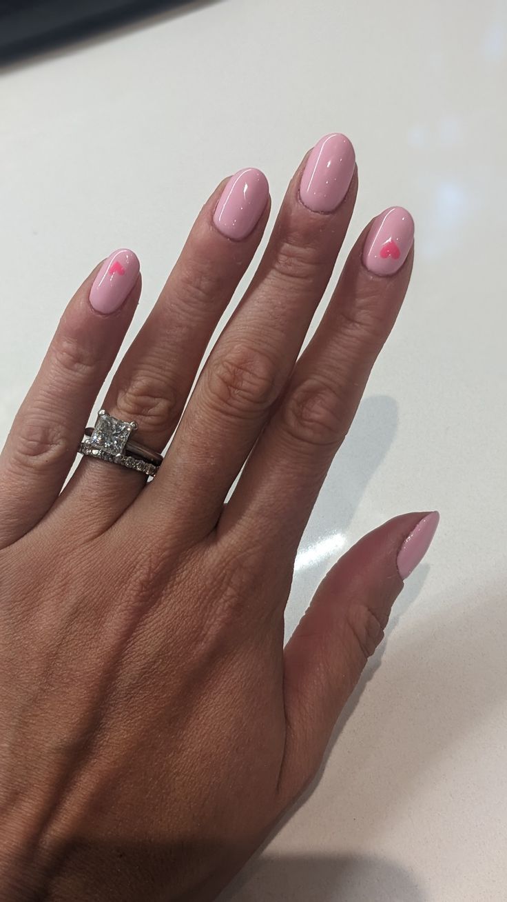 Chic Pastel Pink Nail Design with Glossy Finish and Charming Heart Accents.