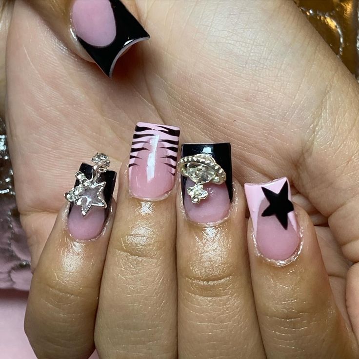 Chic Bold Nail Design: Polished Pink and Black with Intricate Gemstones and Stylish Stripes.