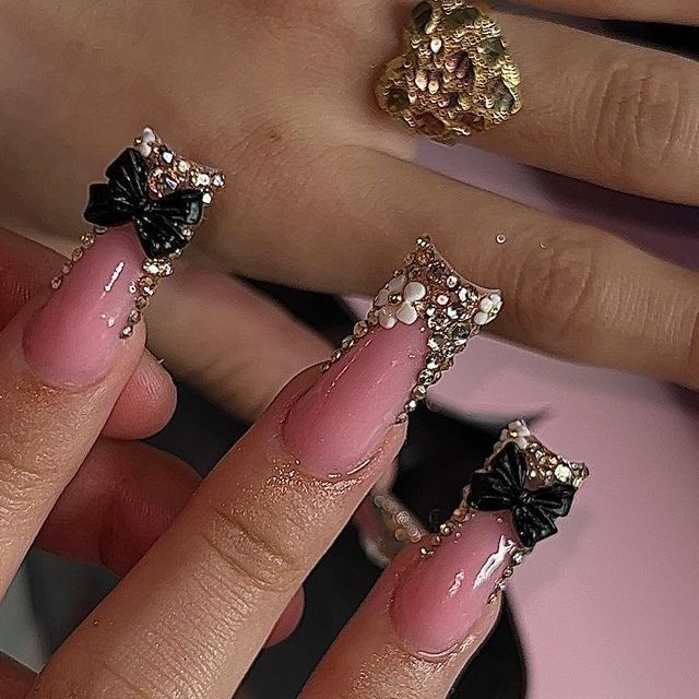 Chic Whimsical Nail Design: Long Pink Nails Adorned with Black Bows and Pearls