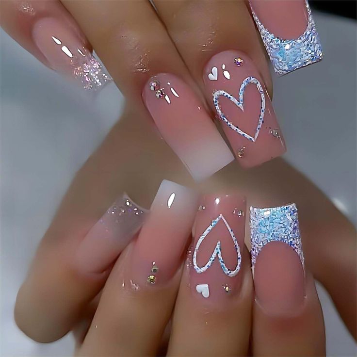 Elegant Pink and White Gradient Nail Design with Charming Heart Motifs and Sparkling Accents.