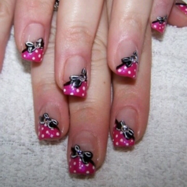 Cheerful Pink Polka Dot Nails with Whimsical Black Bow Tips for a Stylish Look.