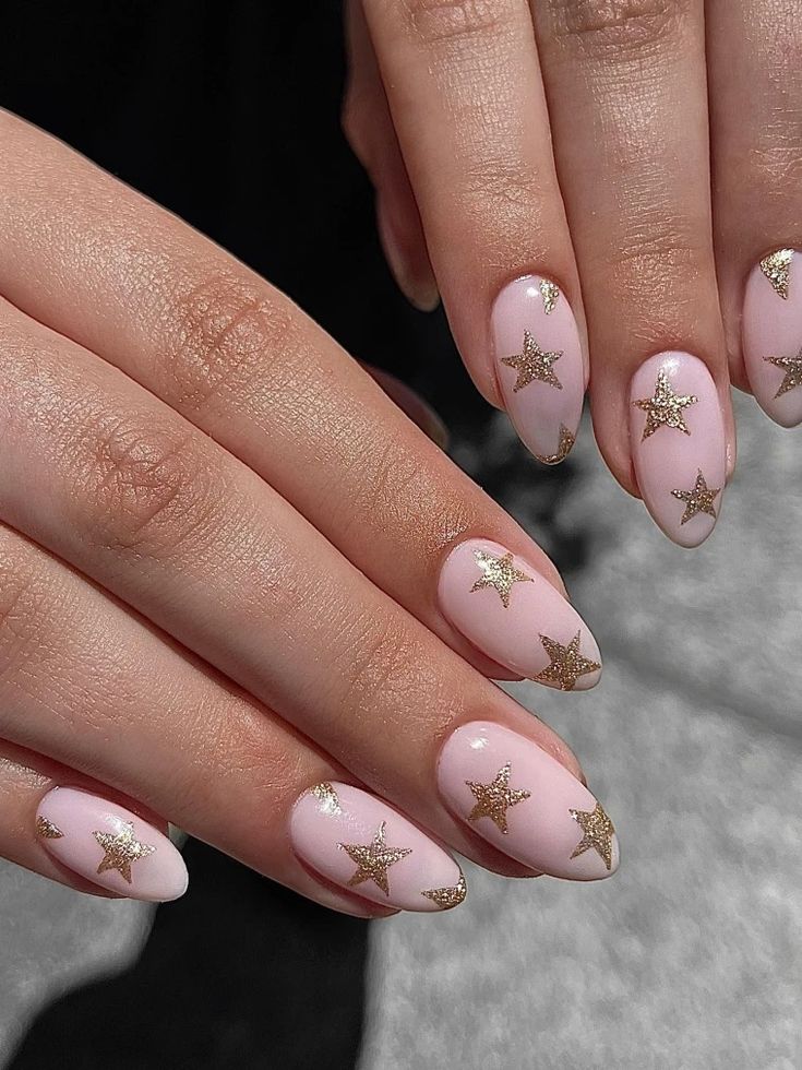 Whimsical Starry Nail Design: Soft Pink Polish with Glamorous Gold Star Embellishments