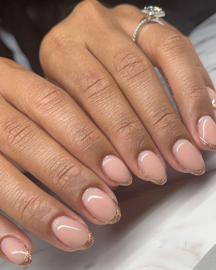 Sophisticated Nude Nail Design with Glossy Finish and Subtle Gold Glitter Tips