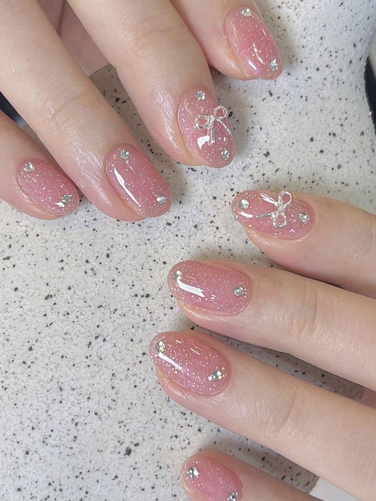 Elegant Pink Glitter Nail Design with Silver Studs and Bow Accents