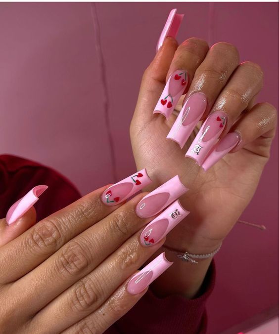 Playful and Trendy Long Nails with Soft Pink Base and Bold Red Heart Accents.