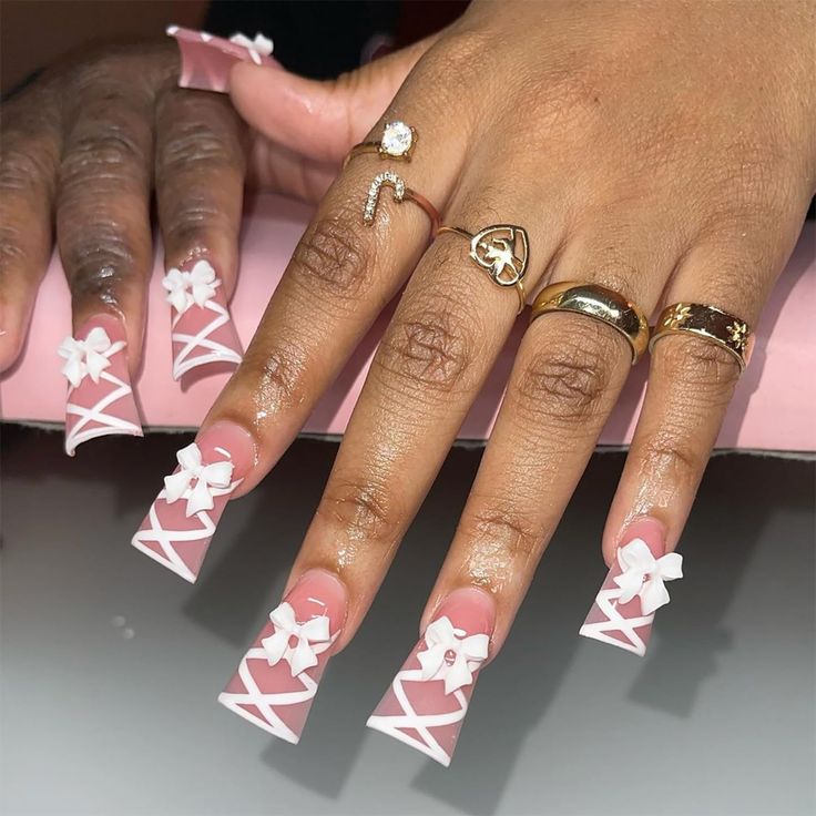 Elegant Nail Design: Long Square Tips with White Bows and Crisscross Patterns on Soft Pink Base.