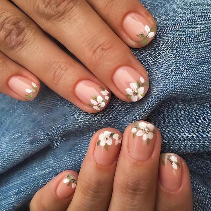 Elegant Floral Nail Design with White Flowers and Green Leaves on a Soft Nude Base.