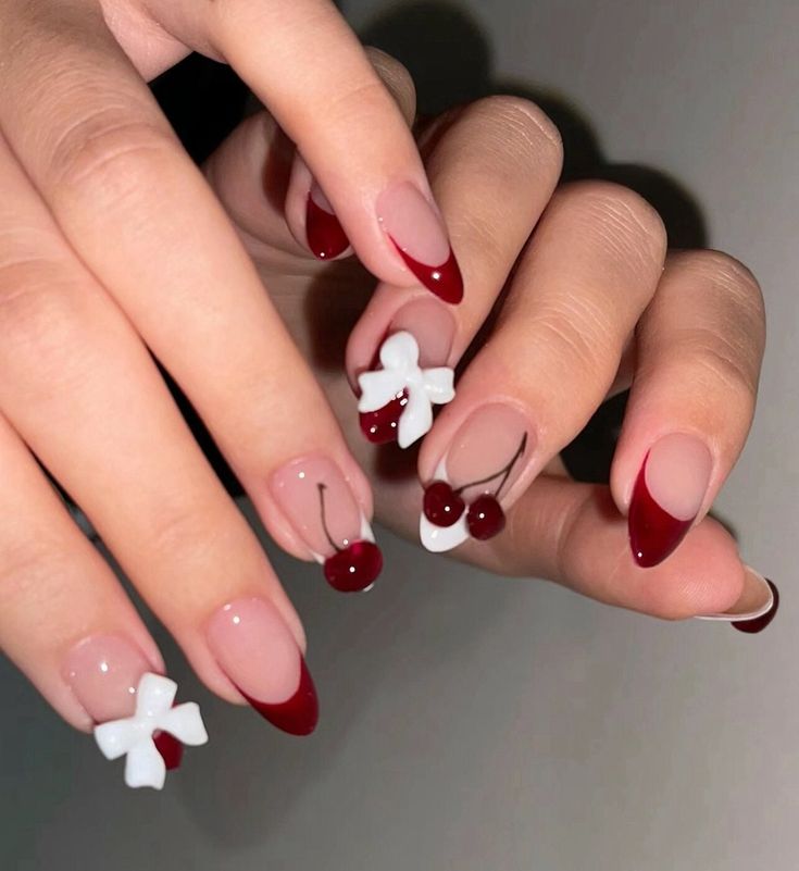 Chic Cherry-Inspired Red and Nude Nail Design with Playful White Bows.