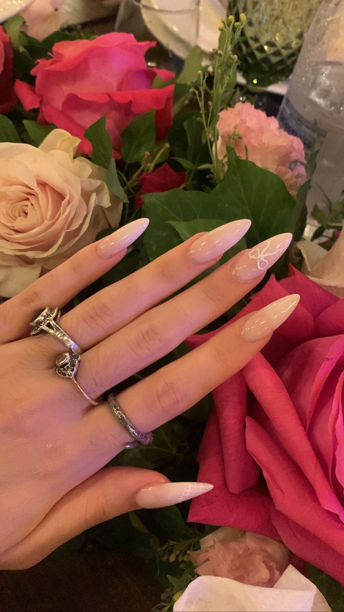 Sophisticated Almond-Shaped Nude Nails with Elegant White Art and Floral Accents.