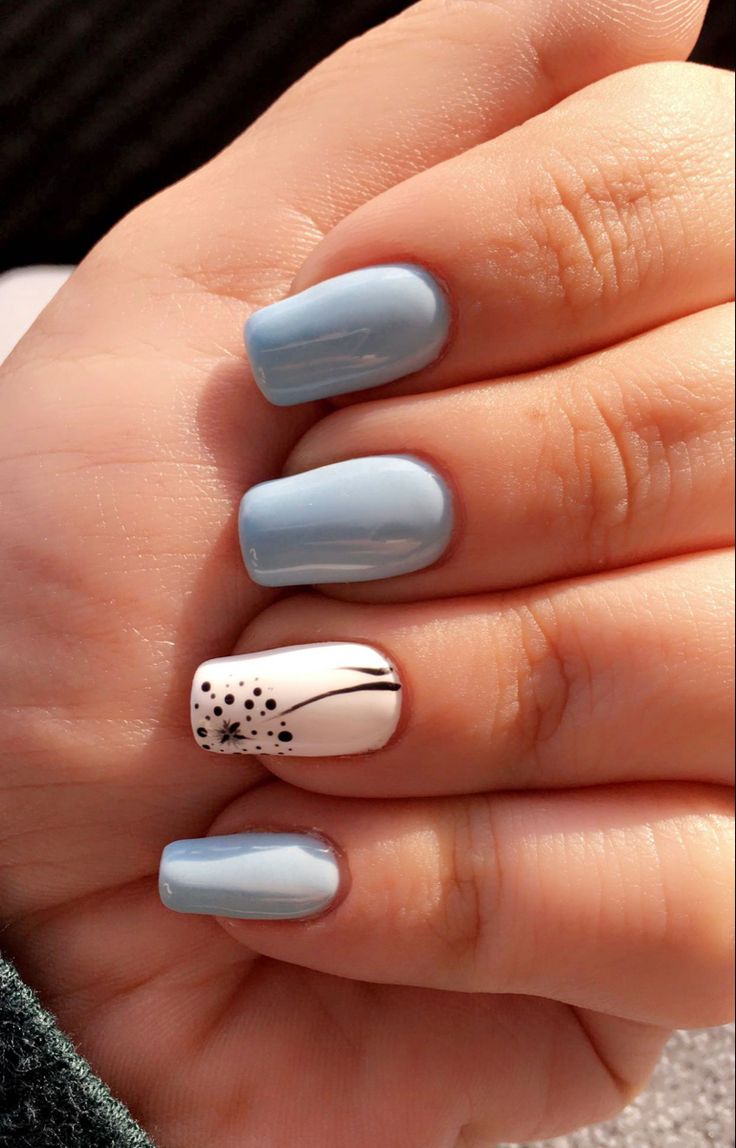 Elegant Soft Blue Nail Design with Striking White Accent and Artistic Black Patterns.