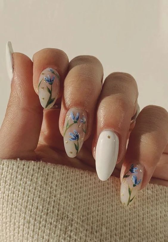 Chic Floral Nail Design: Soft Blue Blooms on Nude with Elegant White Accent and Glitter Accents