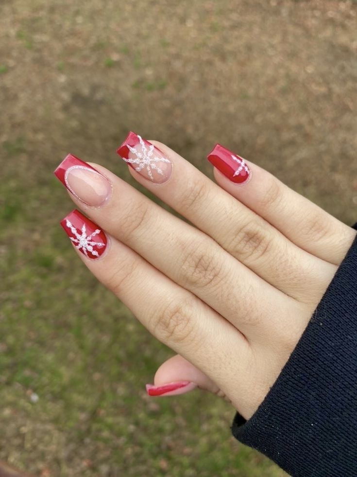 Elegant Festive Red Nail Design with Snowflake Accents and Playful Finishes.