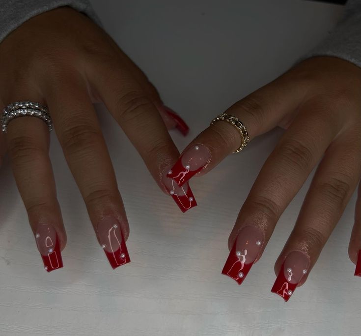 Elegant Red and Clear French Tip Nail Design with Intricate White Accents.