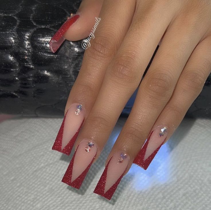 Glamorous Angular French Tip Nail Design with Nude, Bold Red, and Glitter Accents.