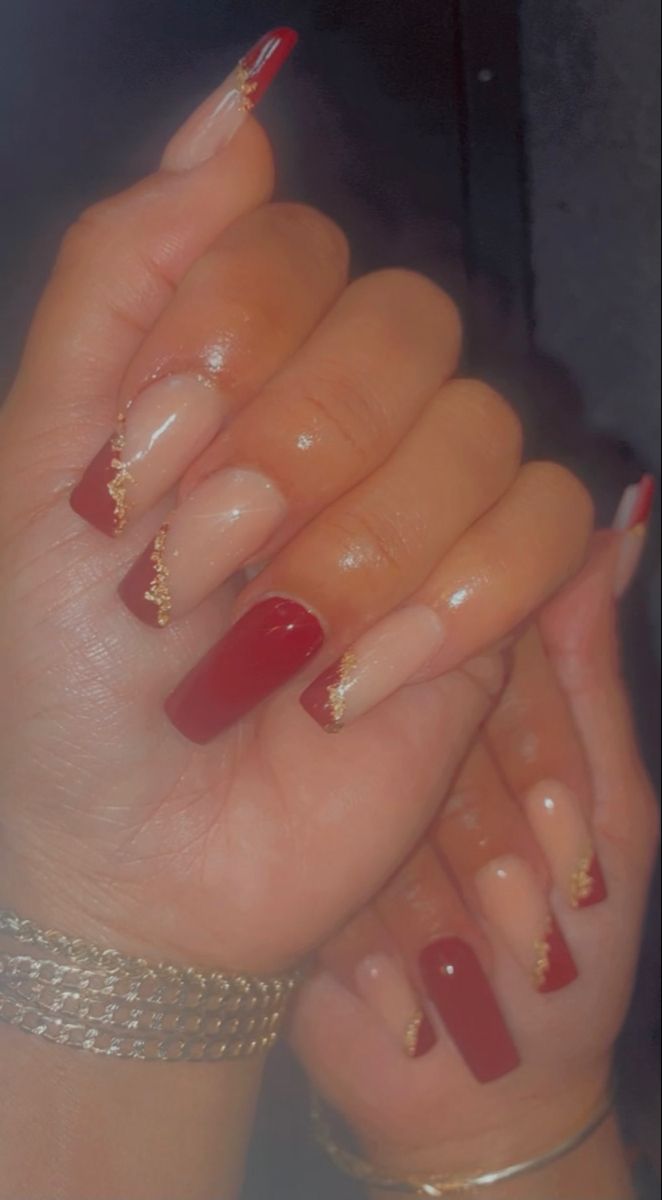 Sophisticated Deep Red and Nude Nail Design with Glossy Finishes and Gold Accents.