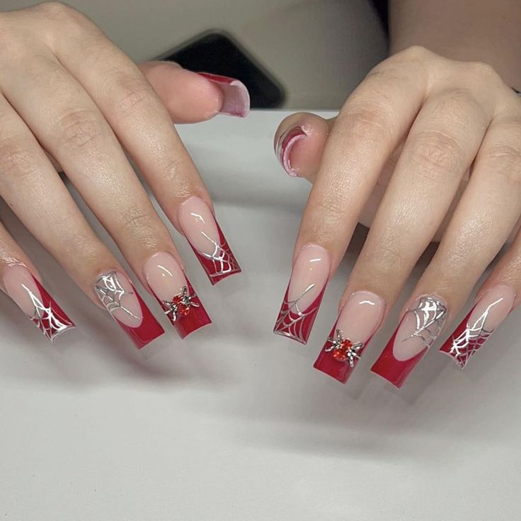 Bold Red and Nude Nail Design with Intricate Spider Web Patterns and Glamorous Sparkles.