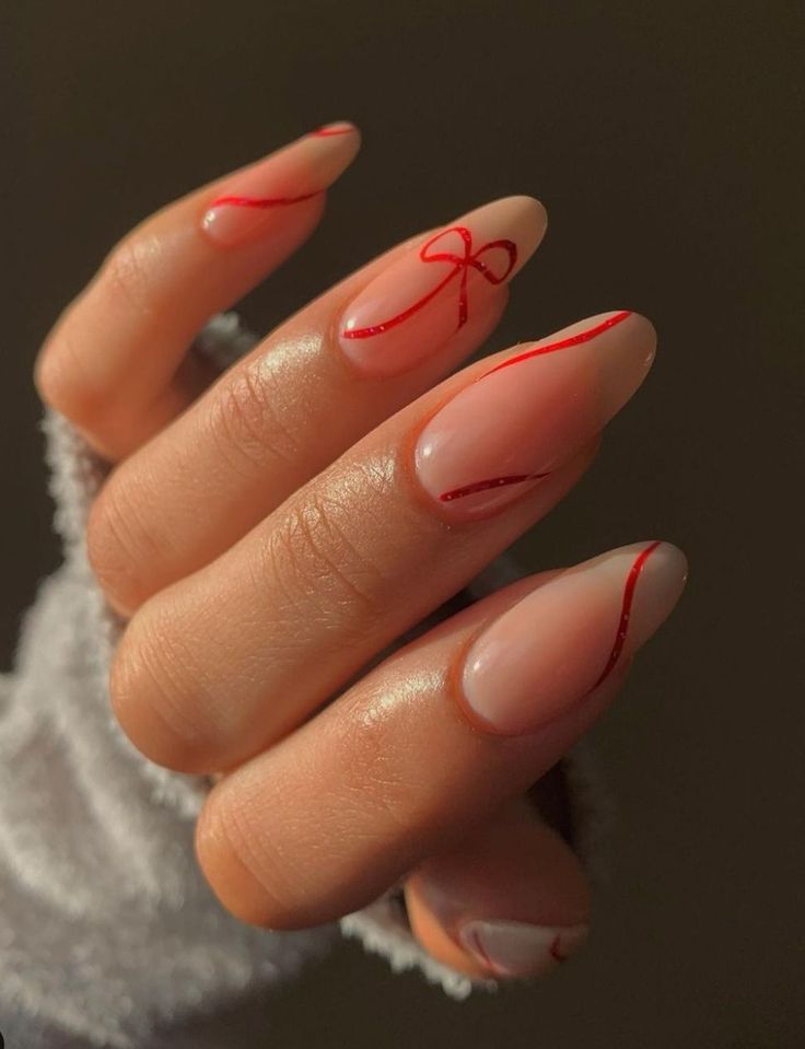 Whimsical Nude and Red Nail Design with Ribbon-Like Accents.