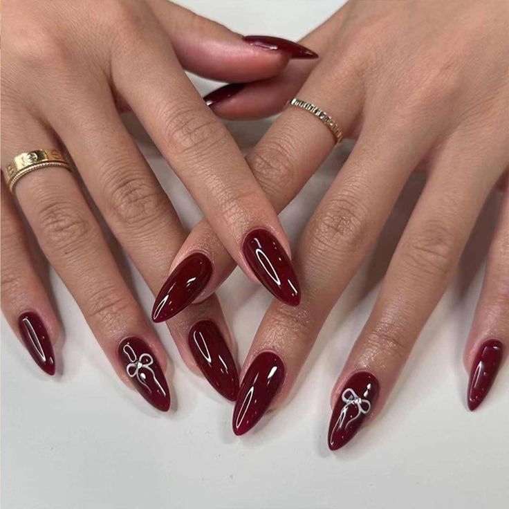 Sophisticated Burgundy Almond Nails with Silver Accents and Minimalist Rings.